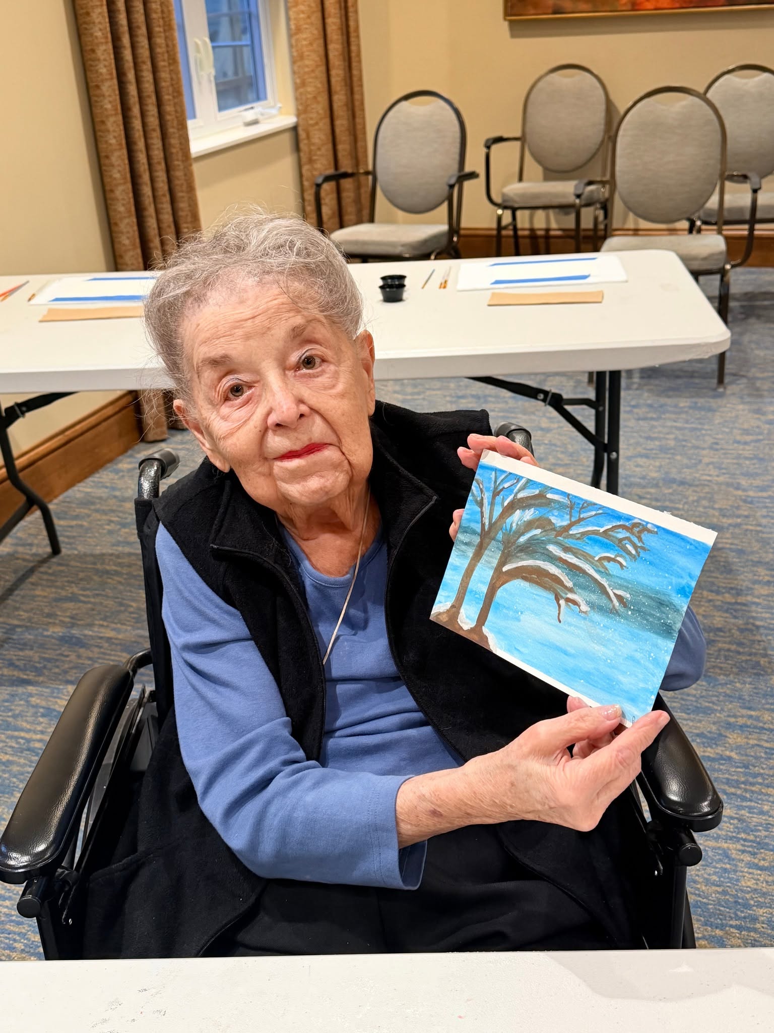 A resident showing the winter landscape she painted in art class
